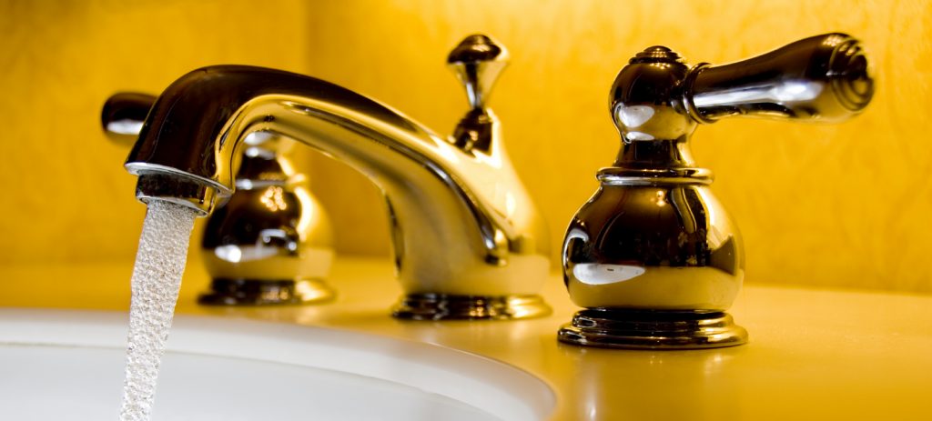 Bathroom taps switched on showing running water from the tap.